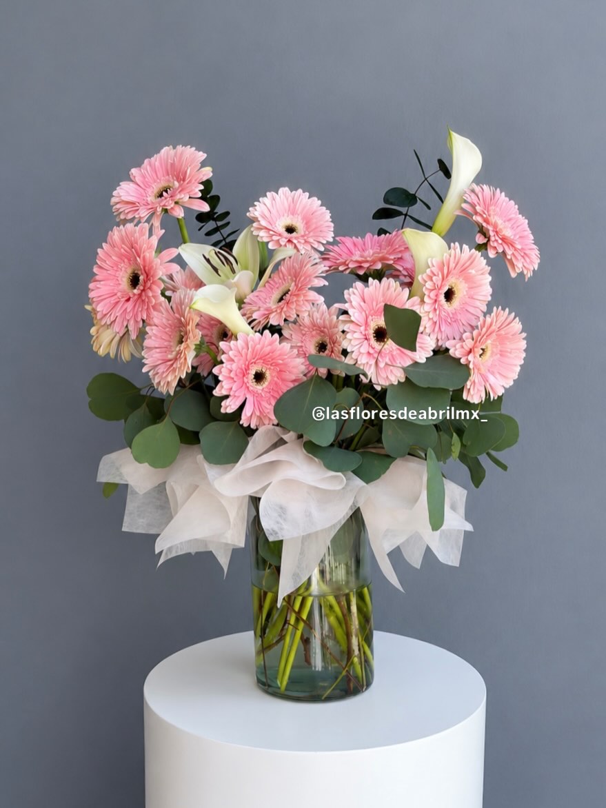 Gerberas rosas y alcatraces blancos en florero de cristal
